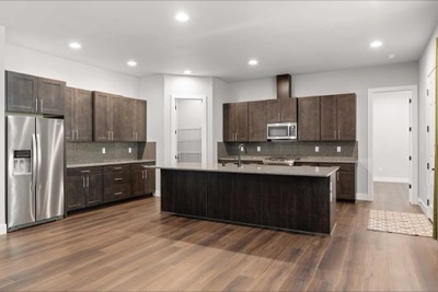 Kitchen of a completed home with dark cabinetry and a quartz island