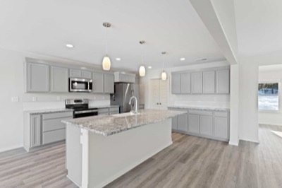 Kitchen of a completed home with granite counters and pendant lighting