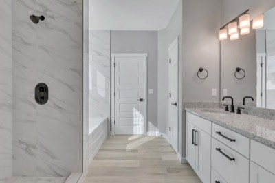 Primary bathroom of a completed home, double vanity and tiled shower