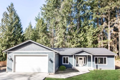 Completed home on the owner’s land with tall firs behind