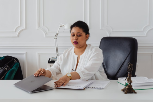 a woman sitting on the black leather seat at the white table with laptop